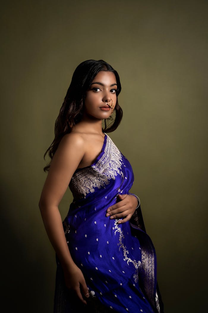 Beautiful portrait of a woman wearing a vibrant blue saree in a traditional pose.