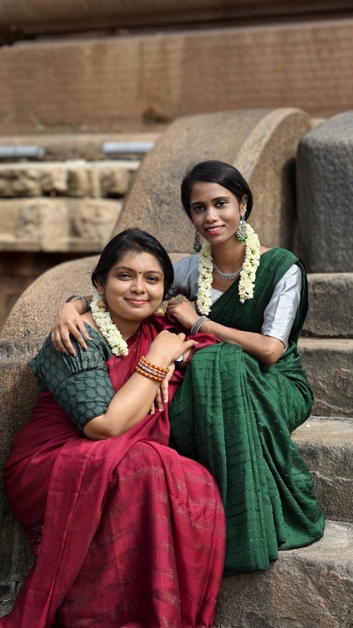 services-04 Two women in sarees pose outdoors in Thanjavur, reflecting traditional Indian culture.