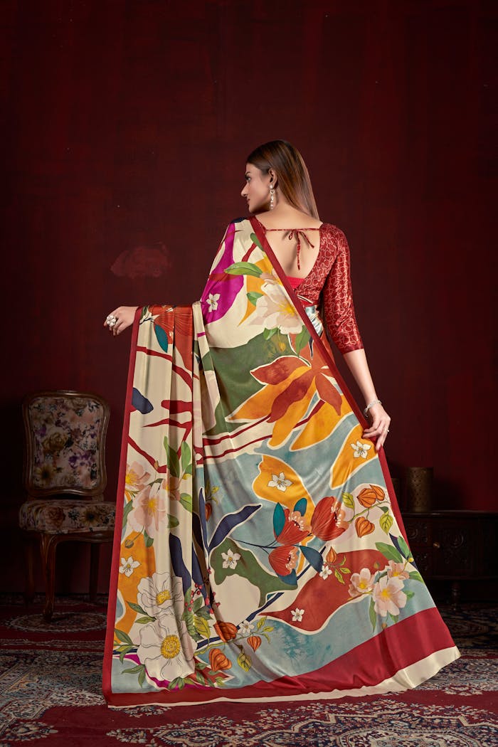 Woman showcasing vibrant floral saree in traditional Indian setting.