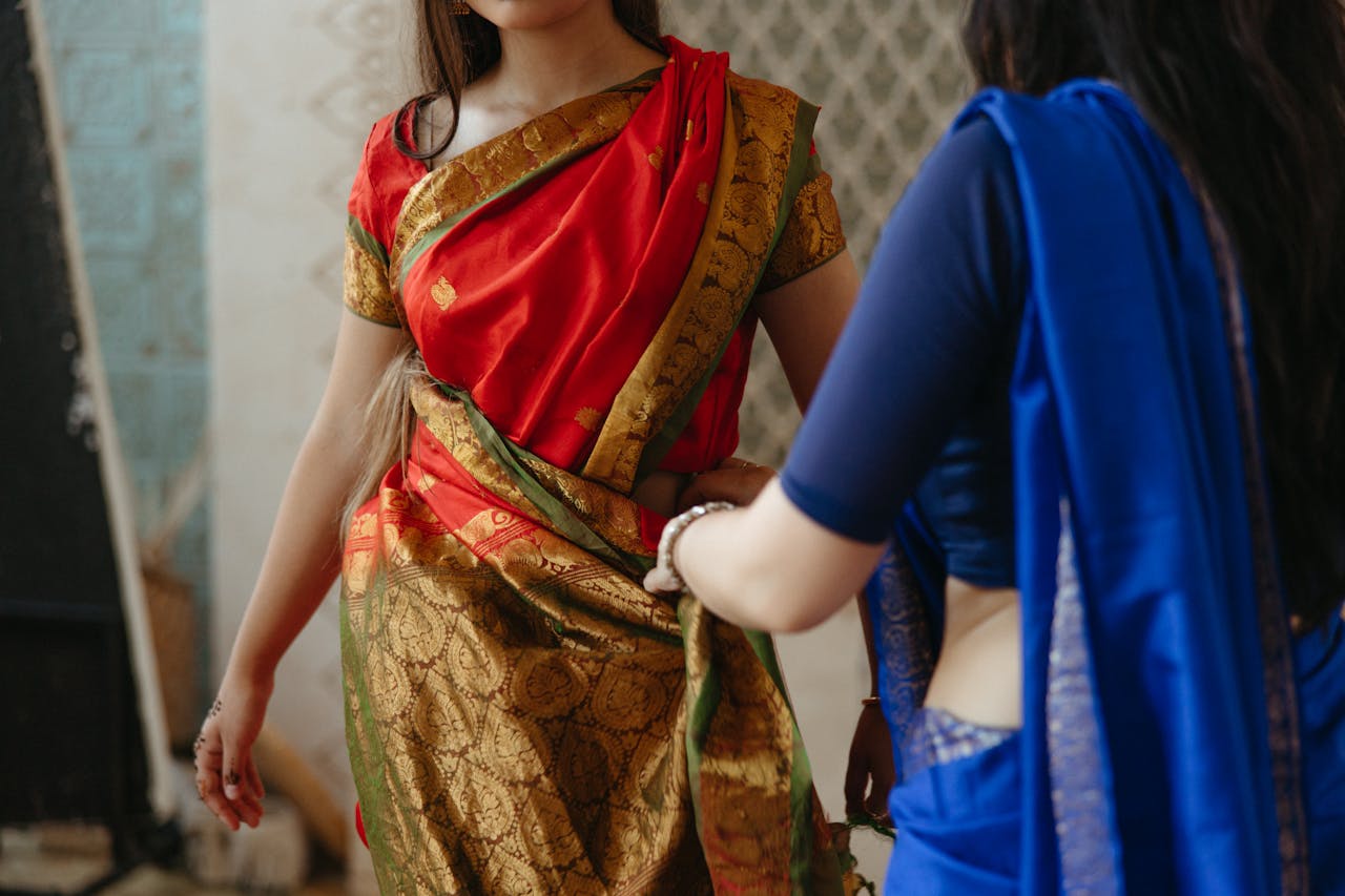 who-we-are Women wearing vibrant sarees indoors, highlighting traditional Indian attire and culture.